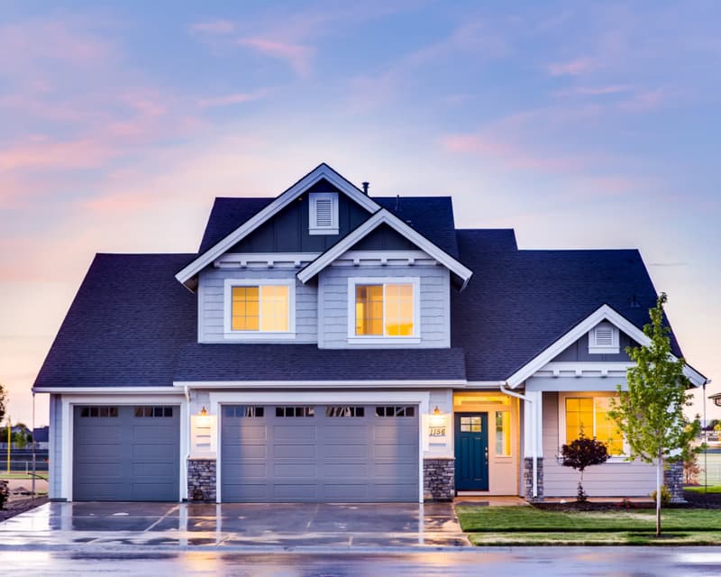 A two-story home with its lights on at dusk